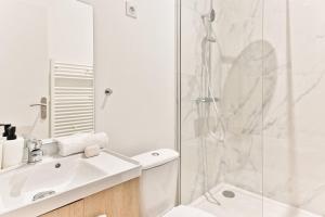 a white bathroom with a sink and a shower at Appartement spacieux à 5 minutes de la capitale in Bagnolet