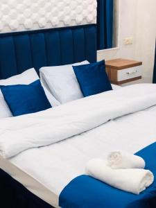 uma cama com lençóis azuis e brancos e almofadas azuis em Nana's House em Batumi