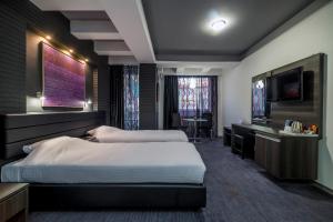 um quarto de hotel com duas camas e uma televisão de ecrã plano em Sienna Apartments em Skopje