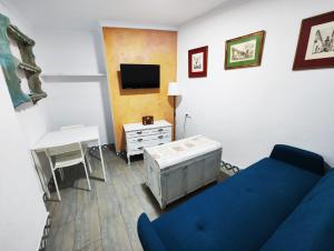 a living room with a blue couch and a tv at Apartamento PUERTA DE CÓRDOBA in Carmona