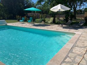 uma piscina com cadeiras e um guarda-sol em La Miougrano em Plan-dʼOrgon