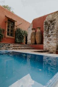 Dos jarrones grandes están sentados junto a una piscina. en Hotel Casa De Quino, en Querétaro
