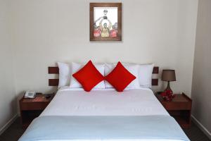 a bedroom with a white bed with red pillows at Hotel Cienciano in Cusco