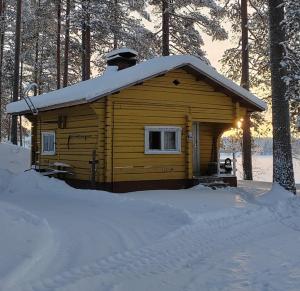 Cabaña de madera con techo cubierto de nieve en Talo Kainuun korvessa Kiekinkoskella, en Kuhmo