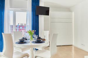 tavolo bianco da pranzo con sedie bianche e televisore di Golden Hour Apartments- Plac Słowiański 43 a Świnoujście