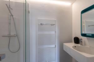 a white bathroom with a shower and a sink at Chez RG in Bruges