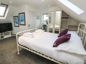 una camera da letto con un letto bianco con cuscini viola di Alice Cottage a St. Agnes 