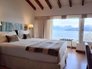 een slaapkamer met een groot bed en een groot raam bij Sol Arrayan Hotel & Spa in Villa La Angostura