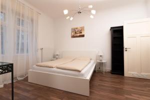 een witte slaapkamer met een bed en een kroonluchter bij Altbau-Apartment im Westend I Küche I Hochparterre in Wiesbaden