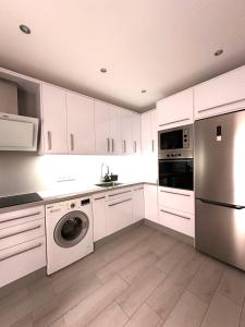 a kitchen with white cabinets and a washer and dryer at Apartamento costero, los Abrigos. in Los Abrigos
