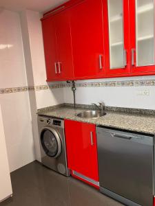 a kitchen with red cabinets and a washing machine at Sobrecueva Paraiso I in Cangas de Onís