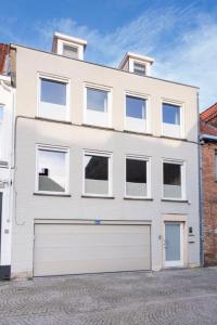 a white building with a white garage door at Chez RG in Bruges