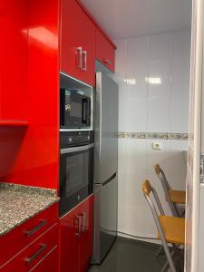 a kitchen with red cabinets and a refrigerator at Sobrecueva Paraiso I in Cangas de Onís