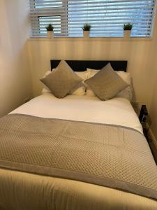 a large bed with pillows in a bedroom with a window at New Sandpiper Apartments in Fleetwood