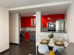 a kitchen with red cabinets and a table and chairs at Sobrecueva Paraiso I in Cangas de Onís