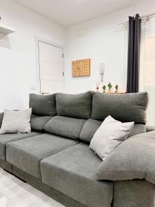 a gray couch in a living room with pillows at Apartamento costero, los Abrigos. in Los Abrigos