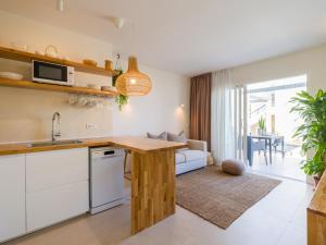 een keuken en een woonkamer met een tafel en een bank bij Apartamento MOJO a 100mts de la playa de Corralejo in Corralejo