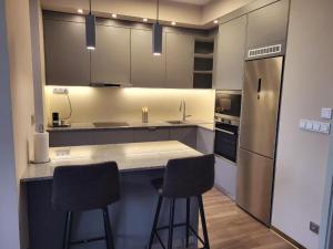 a kitchen with two bar stools and a refrigerator at Modern Living in Budapest in Budapest