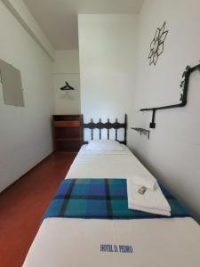 a small bedroom with a bed with a blanket at Dom Pedro Hotel in Petrópolis