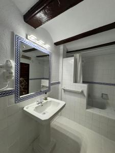 a white bathroom with a sink and a mirror at Garden Suites Xativa in Xàtiva