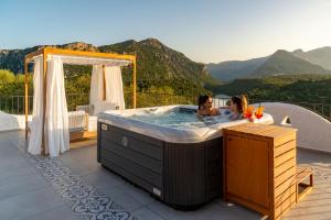 two women in a hot tub on a patio with mountains at Hotel Villa Cedrino in Dorgali