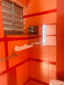uma casa de banho em azulejo laranja com um lavatório e um espelho. em Villa JFK2 em Ouagadougou