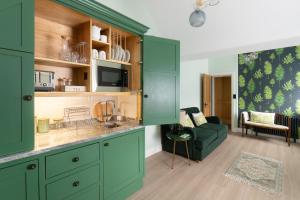 cocina con armarios verdes y sala de estar. en Apartments at Number 16 - The Jolly Coopers, en Hampton