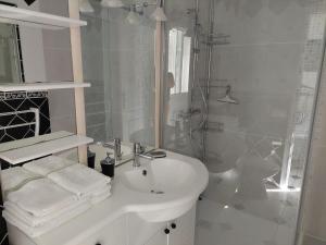 a white bathroom with a sink and a shower at Résidence Villa Nova in Tiuccia
