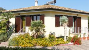 ein Haus mit Palmen und Blumen davor in der Unterkunft Bari Sardo Le More Suite 1 in Bari Sardo