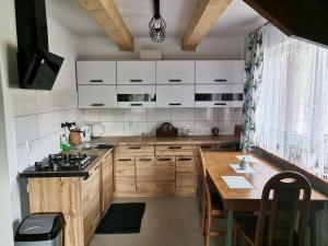a kitchen with wooden cabinets and a wooden table at Dom na Smyrakach in Zawoja