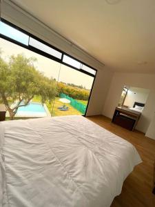 ein Schlafzimmer mit einem weißen Bett und einem großen Fenster in der Unterkunft Terraviva Chincha® Casa de Campo Natural y hermosa in Chincha Baja