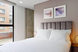 een slaapkamer met een groot wit bed en een raam bij Apartamento 201 Kappa in Bogota