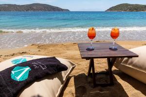 two wine glasses sitting on a table on the beach at Vassilia on the beach Serifos in Livadakia