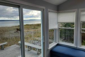 a room with two windows with a bench and a view of the water at Beach Bliss, Great View in Guysborough