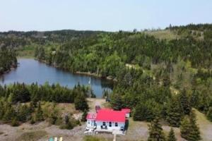 a large house with a red roof next to a lake at Beach Bliss, Great View in Guysborough