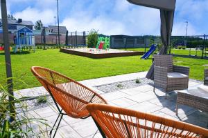 un patio avec des chaises et une aire de jeux avec un toboggan dans l'établissement Domki Przystań Kotwica, à Jastrzębia Góra