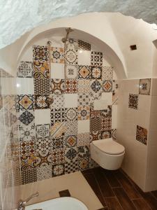 a bathroom with a toilet and a tiled wall at LocoMura in Locorotondo