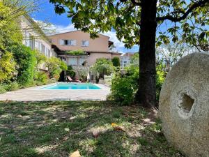 a house with a swimming pool in front of a tree at les petites terrasses in Grasse