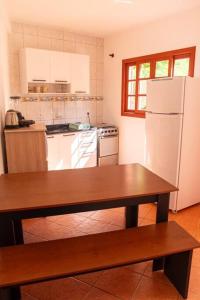 a kitchen with a table and a white refrigerator at Apto com vista para Montanha - nr 1 in Garopaba