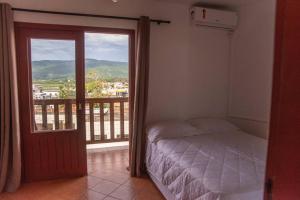 a bedroom with a bed and a balcony with a view at Apto com vista para Montanha - nr 1 in Garopaba
