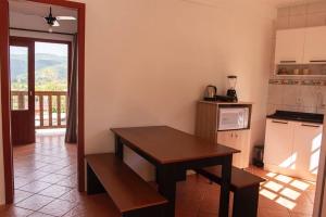 a kitchen with a wooden table and a table and a counter at Apto com vista para Montanha - nr 1 in Garopaba