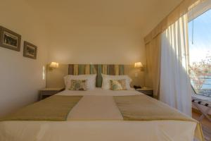 a bedroom with a large white bed with a window at Sol Arrayan Hotel & Spa in Villa La Angostura