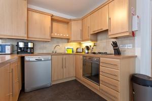 a kitchen with wooden cabinets and a white dishwasher at Luxury ground floor 2 Bedroom apartment Bangor. in Bangor
