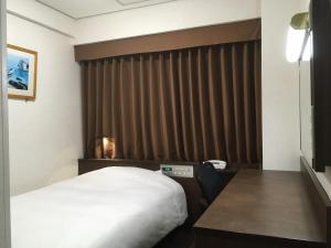 a hotel room with a bed and a wooden headboard at Hotel Alpha-One Ogori in Yamaguchi
