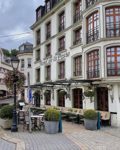 a building with tables and chairs in front of it at Hotel de la Poste - Relais de Napoleon III in Bouillon