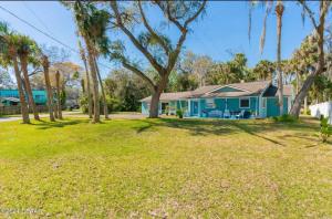 a blue house with palm trees in the yard at Tomoka River Guest House in Ormond Beach