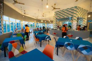 a restaurant with blue tables and chairs and people in the background at Beautiful Seaview Superior Room in Bakau in Bakau