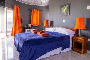 a bedroom with a blue bed with orange curtains at Beautiful Seaview Superior Room in Bakau in Bakau