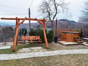 a wooden pergola with a bench and a table at Dom na Smyrakach in Zawoja