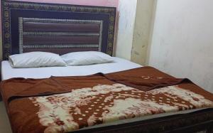 Una cama con una manta marrón y blanca. en H-J Family Hotel en Lahore